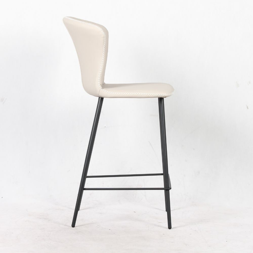 sgabello core colore beige con gambe in metallo nero, vista ambientata accanto a bancone o isola
